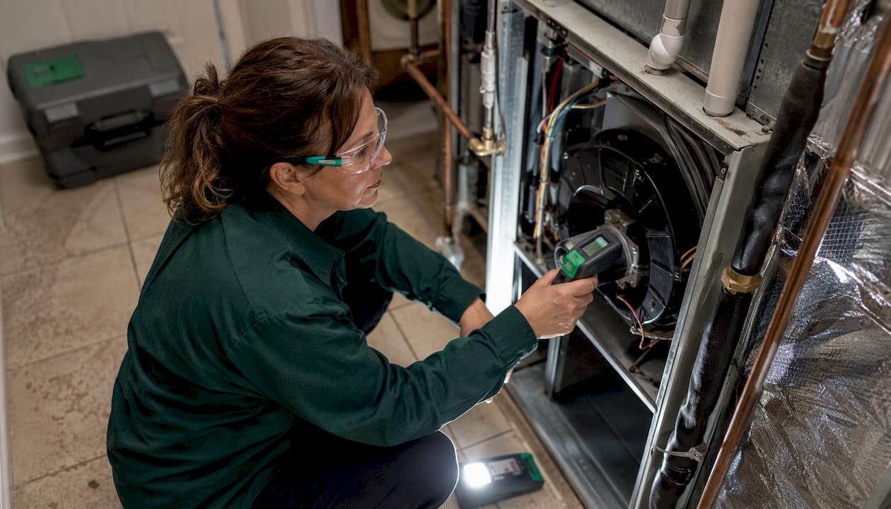 Technician inspecting indoor HVAC furnace components