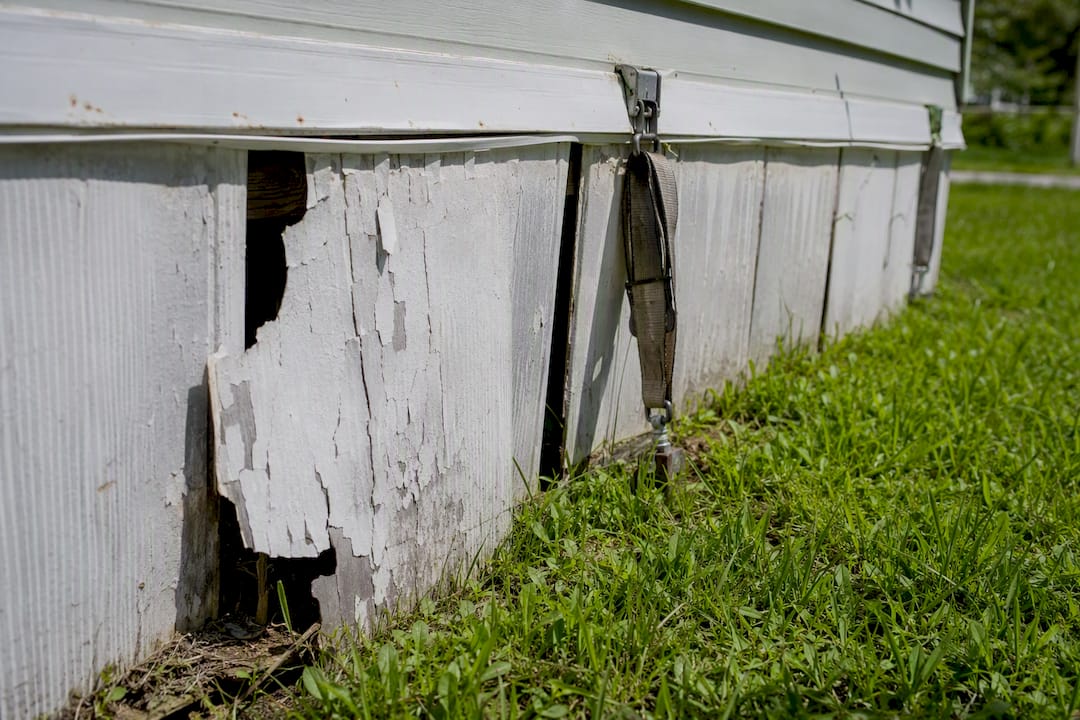Close-up of skirting panel crack and tie-down strap defect