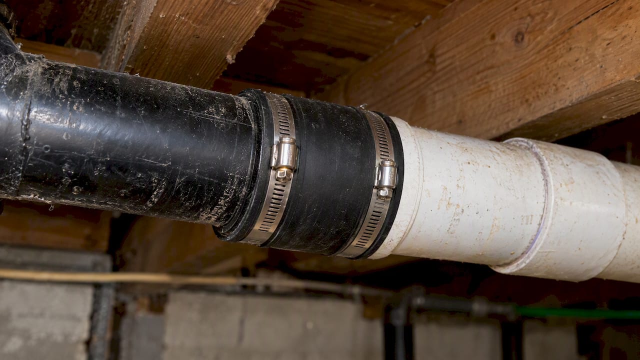 Banded coupling joining black and white drain pipes